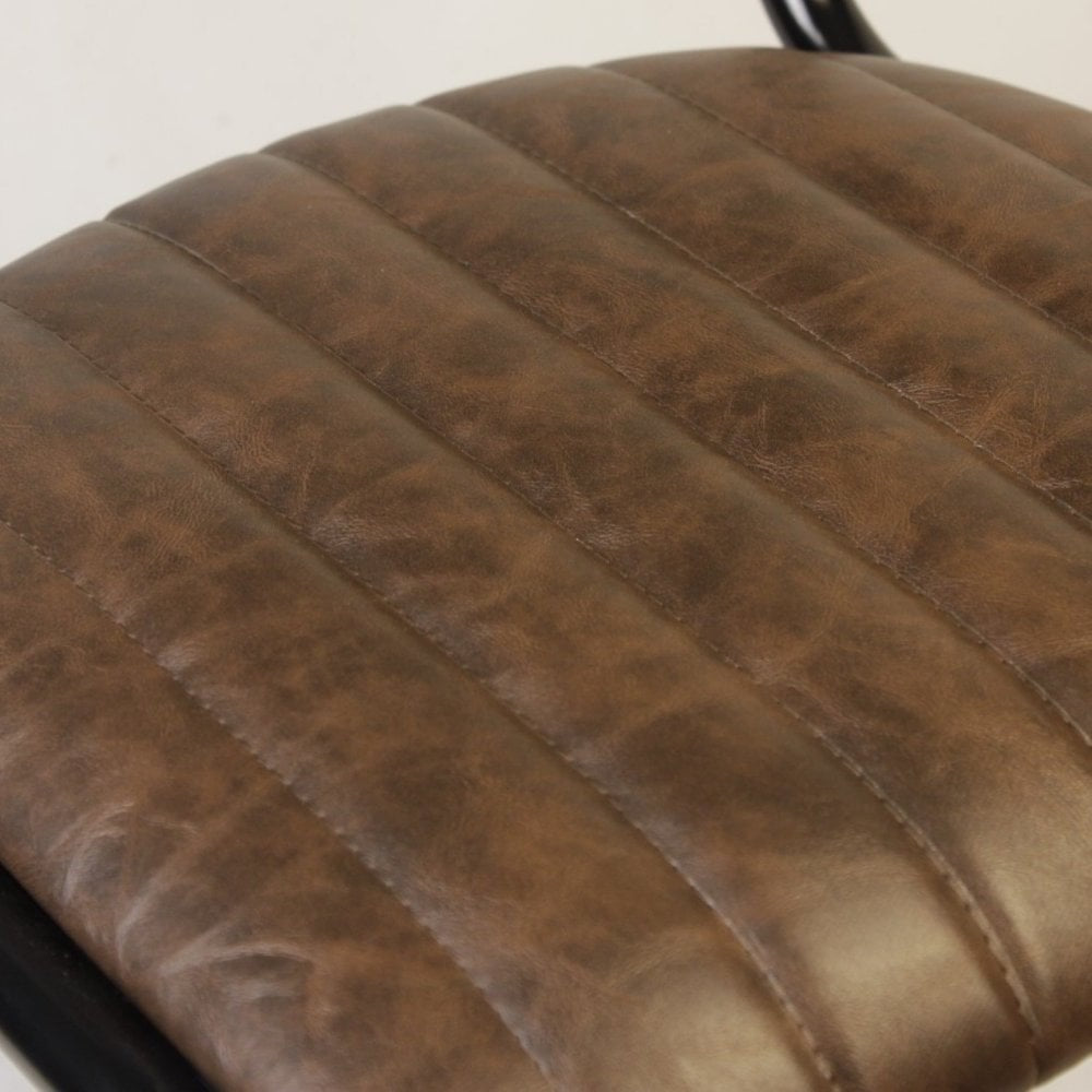 Close-up of the Derby Industrial Side Chair - Faux Leather shows a brown seat with horizontal stitching, a subtly worn texture, and visible black metal edges reminiscent of retro restaurant style.
