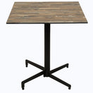 Switch The Vintage Wood Outdoor Laminate Restaurant Table Top, shown on a black metal pedestal base with four feet against a white background, features a rustic, weathered wood look with visible grain and color variations. 2 image