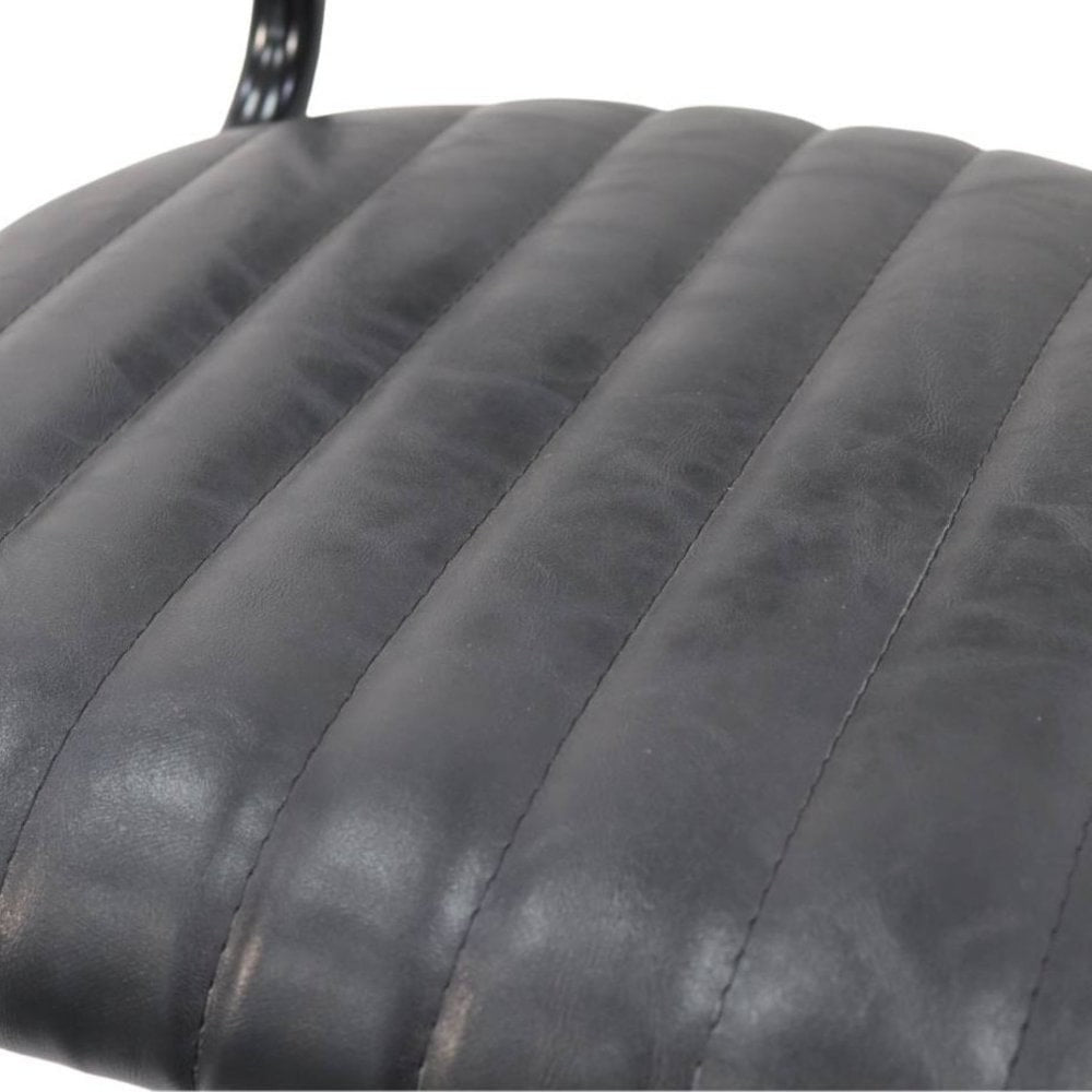 Close-up of the Derby Industrial Side Chair - Faux Leather, featuring a black, ribbed cushion with visible stitching and a glossy texture. A metal leg appears at the top, highlighting the chair’s retro-industrial style.