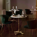 Switch Elegant restaurant interior with round marble tables and dark green velvet chairs, each featuring a Gold Bistro Ornate Four Leg Cast Iron Table Base on polished wooden floors. Tables are set with wine glasses and plates for a sophisticated ambiance. 2 image