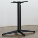 Switch The Trail Black Self Levelling Table Base - Rectangle Single Pedestal by NOROCK features a central column with three angled legs, ideal for indoor or outdoor use. Shown on a concrete floor against a plain white wall. 2 image