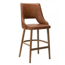Switch The Stone Raw Barstool Frame features a brown faux leather cushioned seat and backrest, solid wood legs, and a footrest, offering comfort and contemporary style in a modern bar stool design. 2 image