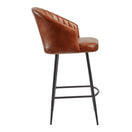 Switch Side view of the Brooklyn Upholstered Bar Stool, perfect for indoor use, featuring a brown genuine leather seat and backrest with vertical stitching, plus black metal legs with a convenient footrest. 2 image