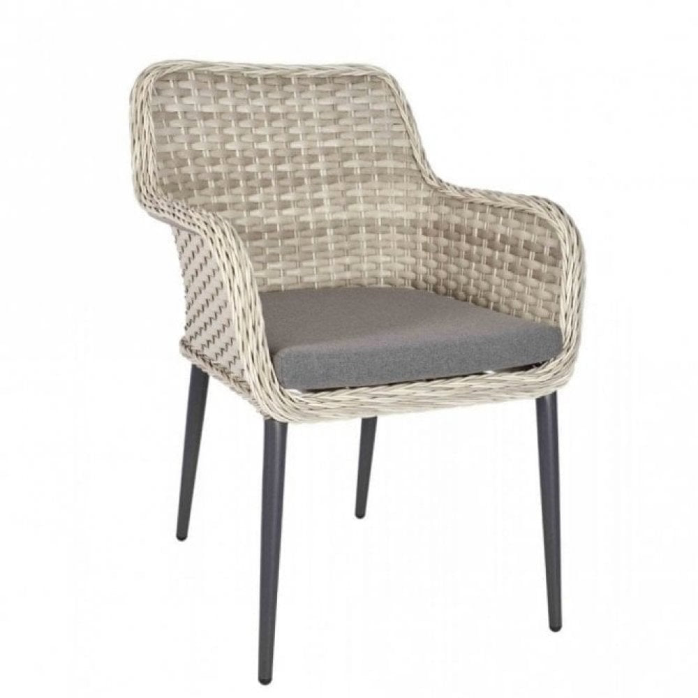 The Bremen Outdoor Stacking Armchair features a wicker curved back with armrests, light brown woven design, gray seat cushion, and slim black legs—perfect as commercial outdoor furniture or a welcoming outdoor armchair.