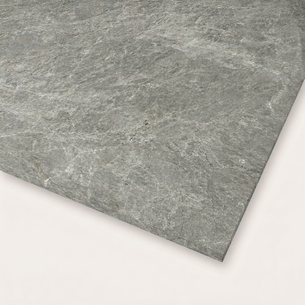A close-up of the Tundra Grey Real Marble Restaurant Table Top - 20mm, featuring a textured rectangular gray stone surface, displayed on a light, neutral background.