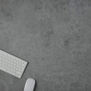 Switch A white computer keyboard and mouse sit at the lower left corner of a Chicago Concrete Effect Restaurant Table Top - 25mm, with most of the gray, textured surface left empty. 3 image