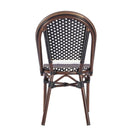 Switch The Carcassonne Bistro Outdoor Stacking Side Chair features a curved wood-look style with an aluminum frame and a woven black-and-white checkered seat and backrest, shown from the back. 2 image