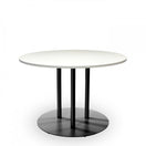 Switch The Valencia Extra Large Black Round Table Base supports a round table with a smooth white top and four black cylindrical legs. The scratch-resistant base stands out against the plain white background. 2 image