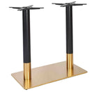 Switch The Zeus Brass Black Table Base - Rectangle Twin Pedestal features two cylindrical black legs with gold-toned lower sections on a brass-plated steel platform, designed to support a tabletop. 1 image